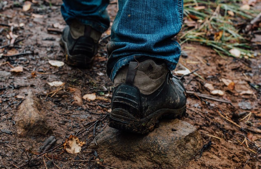 man in blue jeans hiking through a muddy portion of the trail